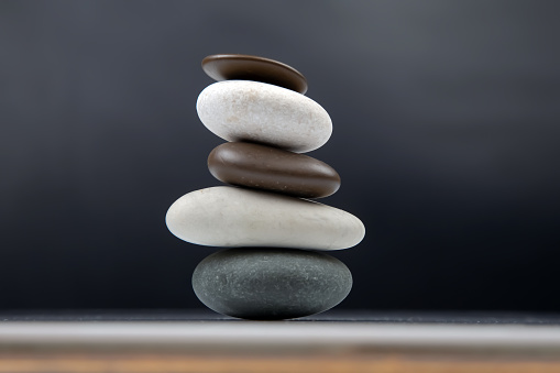 Macro photo of gray pebble stone on top of smaller stones. There are black abstract lines on big stone. Shot in studio with a full frame mirrorless camera.