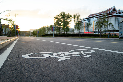 Bicycle sign on asphalt road next to modern buildings