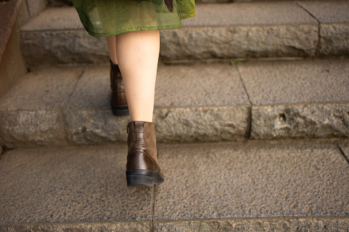 Asian woman sightseeing in Japan.
Strolling through an old Japanese town.
Her feet going up cobblestone stairs. She is wearing boots.
Her face is not in the picture.