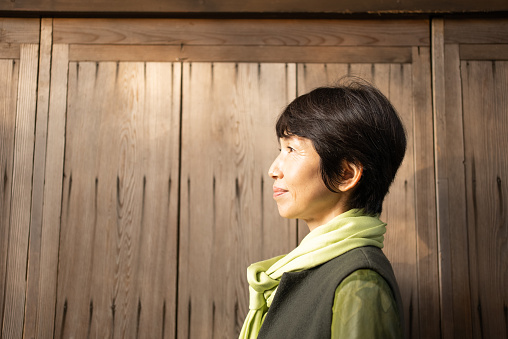 Portrait of an Asian woman.
Taken in front of a wooden wall.
Japanese woman in her 50s.