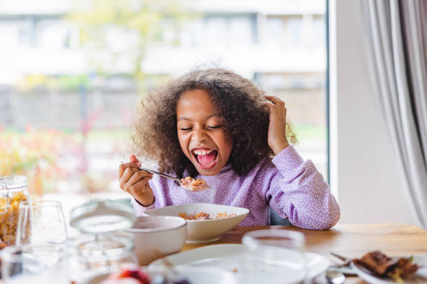 istock Happy Black Little Girl Having Fun While Eating Cereal For Breakfast By A Big Dinning Table In A new Apartment 1448623375