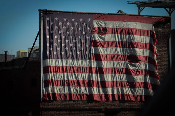 istock Tattered American flag handing on an old building 1448626263