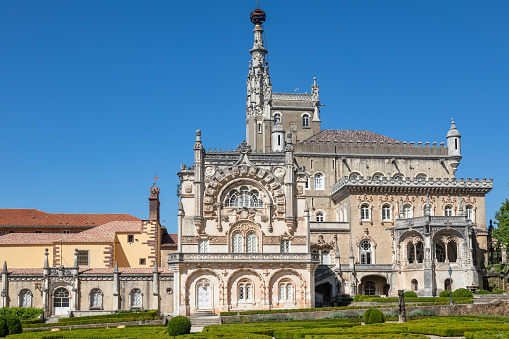 The Bussaco Palace with an ornamental garden against the background of the blue sky on a summer day. Luso, Portugal