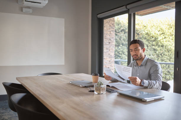 istock Business man and reading documents while planning or brainstorming accounting ideas in a financial firm. Finance, reading and male accountant with paperwork in an office boardroom for plan 1448630650