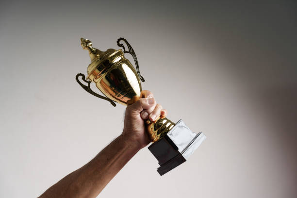 istock Raised hands of old man holding trophy. Isolated, close up. 1448632112