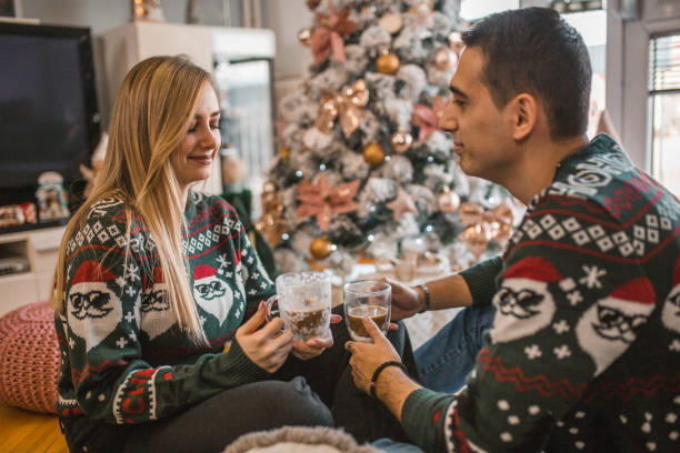 istock A man and a woman drink coffee while sitting next to a Christmas tree 1448646017