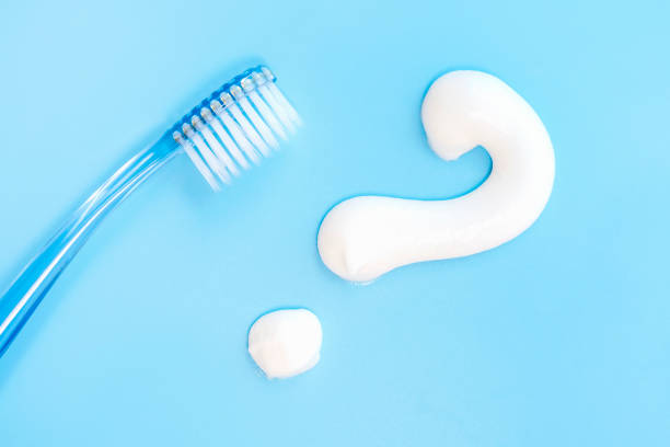 Toothbrush and question mark on blue background close-up, top view. stock photo