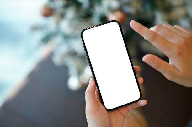 Top view, A female hand holding a smartphone white screen mockup over blurred background. stock photo
