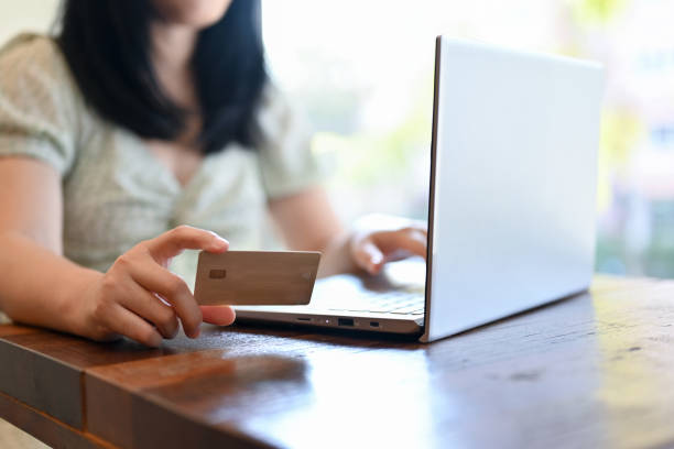 istock An Asian young Asian woman holding a credit card while using laptop at her table. cropped image 1448653650