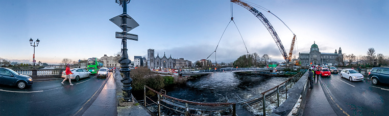 Galway, Ireland - December 12th, 2022 
Brand new pedestrian and cycle bridge over the River Corrib, adjacent to the existing Salmon Weir Bridge captured being welded into position carried precisely by gigantic crane on Monday 12th December. The bridge was constructed on the grounds of the cathedral carpark over past weeks.