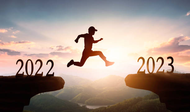 istock 2023 New Year's concept: Man jumping on cliff 2023 over sunset sky background. 1448654620