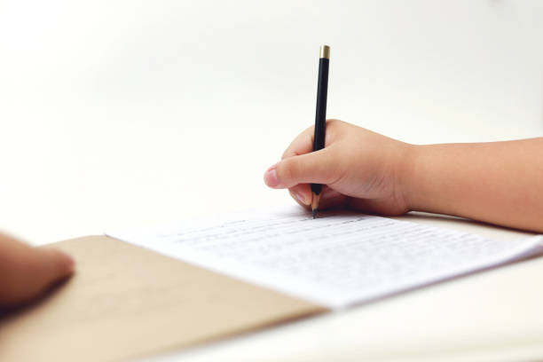istock Boy's hand writing on book and uses a pencil. 1448656498