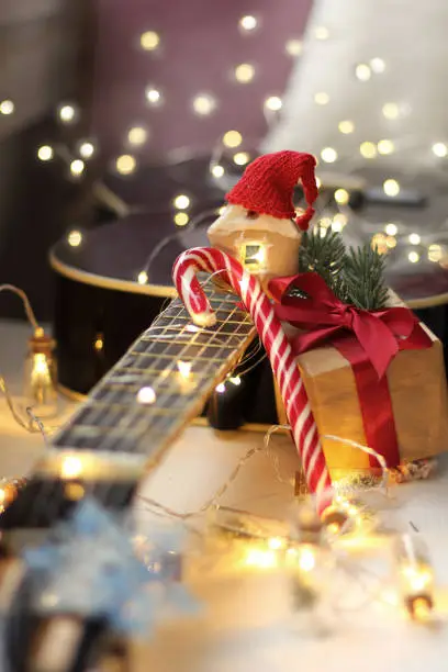 gift, candy and a gingerbread house in a hat against the background of an acoustic guitar with garland lights close-up