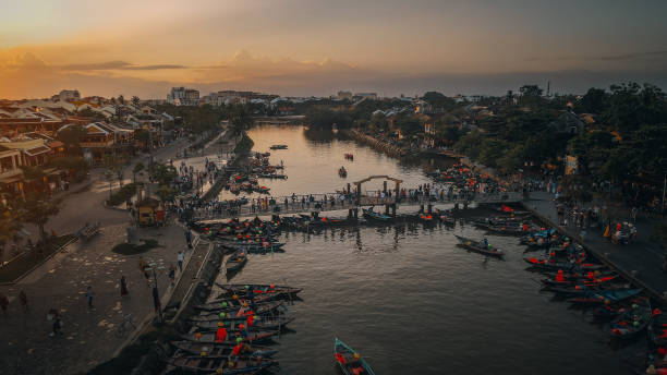 Aerial view of the boats on the river in Hoi An. Drone point of view of colourful long tail boats moored to the causeway on the Thu Bon River, the ancient city of Hoi An, Quang Nam Province, Vietnam. thu bon river stock pictures, royalty-free photos & images