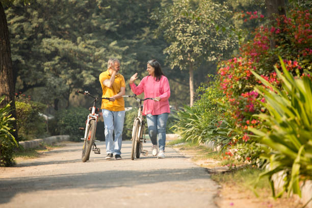 istock Cheerful senior couple walking with bicycles in park 1448669096
