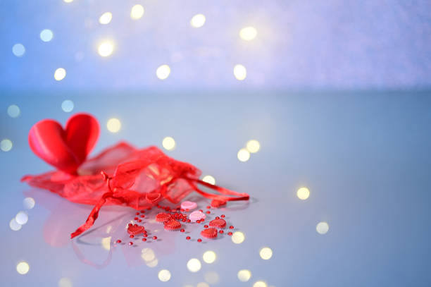 istock Red organza pouch and  heart shaped sequins on blue background 1448672965