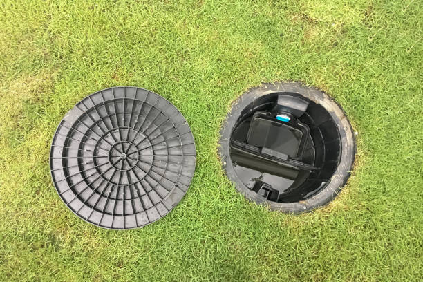 Image of a septic tank grease trap for home use to help collect light liquids such as fats, oils, and grease from the kitchen buried underground with green grass cover. stock photo