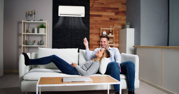 Happy Family Couple Using Air Conditioner Happy Family Couple Using Air Conditioner. Apartment AC air conditioner family stock pictures, royalty-free photos & images