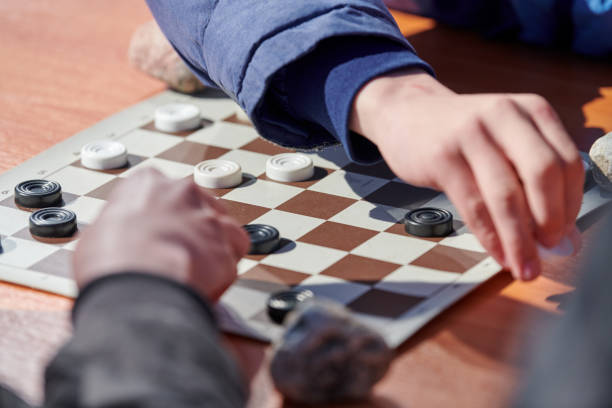 istock Outdoor draughts competition on paper checkerboard on table, close up players hands 1448682812