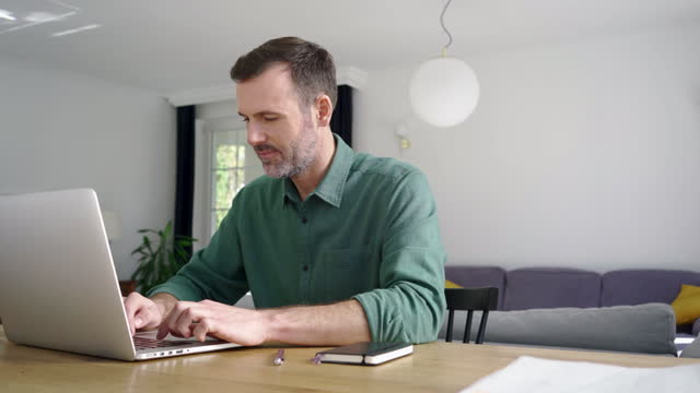 Hombre adulto medio usando computadora portátil para trabajo remoto en casa photo