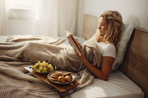 istock Young woman reading a book during morning in a bed. 1448684110