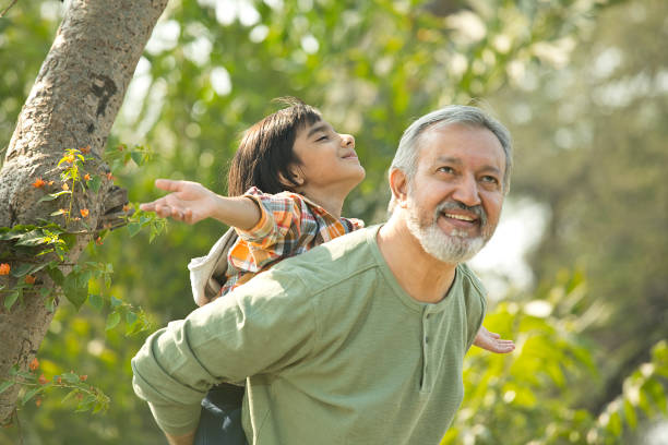 istock Senior man piggybacking grandson in park during weekend 1448685326
