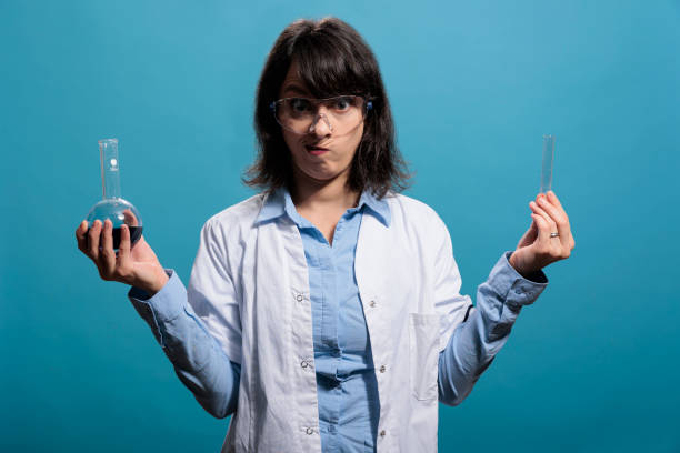 istock Laboratory professional chemist holding glass flasks filled with chemical liquid substances while looking at camera. 1448685353