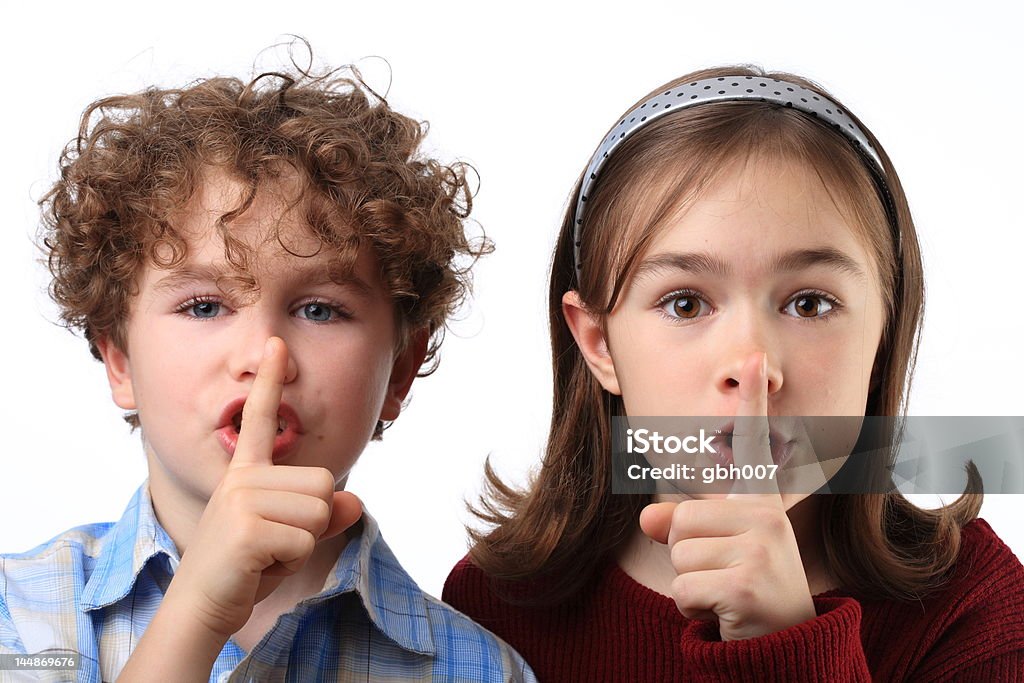 Finger on lips Young girl and boy with fingers on lips Adult Stock Photo