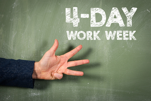 4-day work week. Green chalkboard background and female hand.