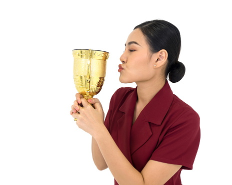 Asian woman in red dress kiss the trophy received from the work done proudly. Portrait on white background with studio light.