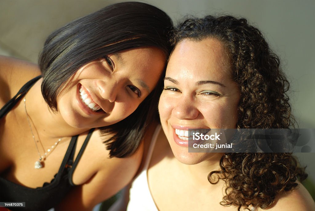 Best friends giggling Attractive young female friends laughing and having fun; very shallow depth of field and natural light Sorority Stock Photo