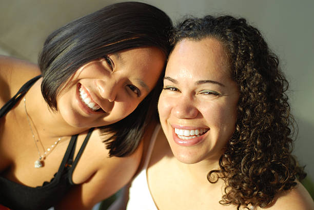 Best friends giggling Attractive young female friends laughing and having fun; very shallow depth of field and natural light sorority photos stock pictures, royalty-free photos & images