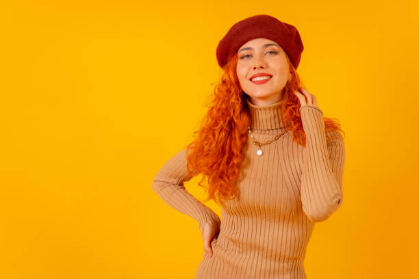 istock Red-haired woman in a red beret on a yellow background, studio shot, copy space 1448705503