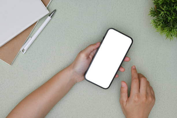 istock A female hand holding a smartphone mockup over her modern minimal office desk. 1448705528