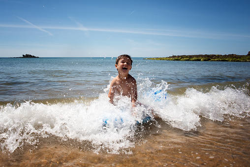 6 year old boy surfing the waves and having fun in the water, the sea.