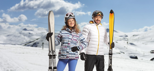 Young couple skiers with helmets and goggles posing on a mountain