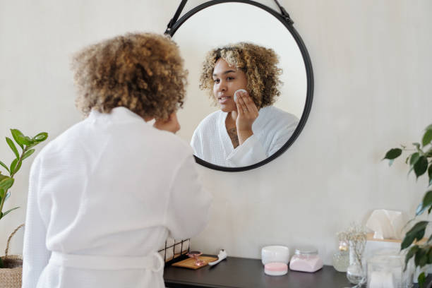 istock Young pretty woman in white bathrobe applying refreshening toner on face 1448709883