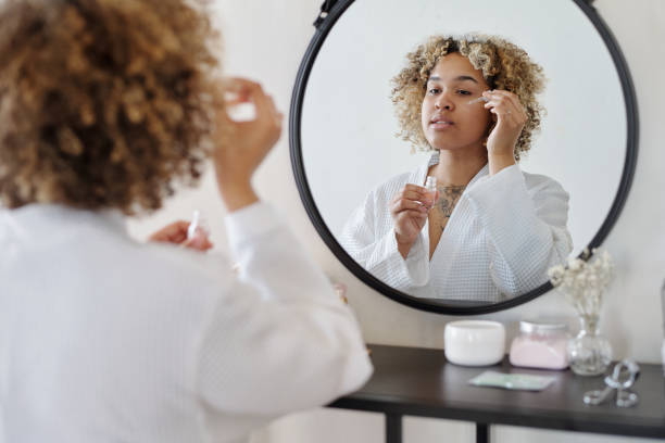 istock Young woman in bathrobe applying serum on face 1448709941