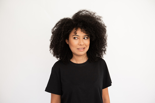 Dissatisfied young woman showing irritation. Hispanic female model with afro hairstyle and brown eyes in black T-shirt making irritated facial expression. Emotion, dissatisfaction concept