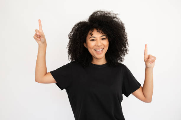 istock Cheerful young woman pointing above at copyspace 1448711859