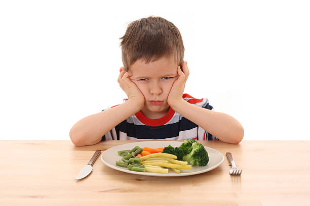istock A boy sulking as he doesn't want to eat the vegetables 144871189