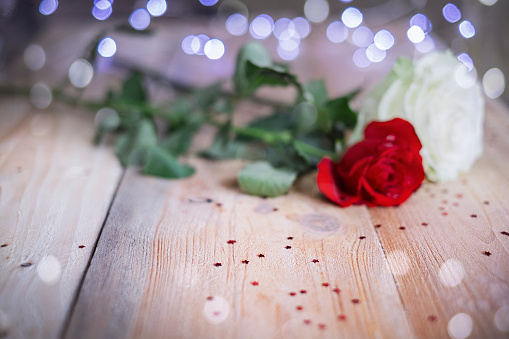 Beautiful white and red roses on wooden table background with mockup. Selective focus.