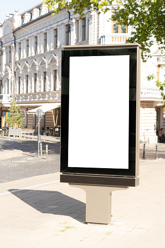 Mockup of blank white city outdoor advertising vertical billboard stand in old town street.