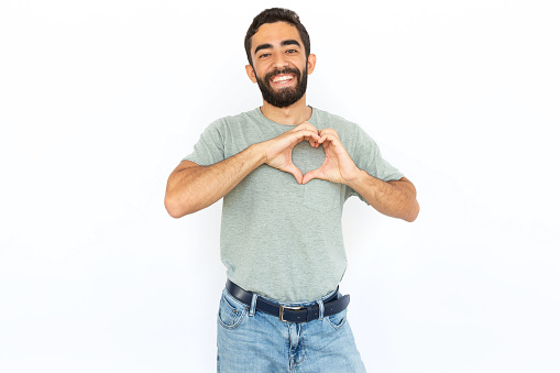 Joyful man showing heart with hands. Young male model making heart symbol, pressing hands to chest. Portrait, studio shot, love concept