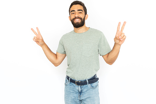 Happy man showing peace sign. Young male model smiling and making victory gesture with both hands. Portrait, studio shot, happiness, victory concept