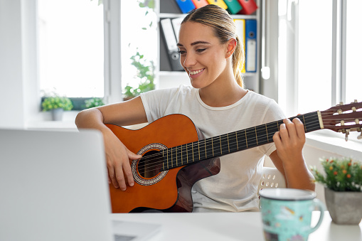 Woman learning to play guitar at home
