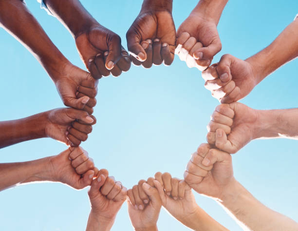 Fist hands, circle and diversity support human rights people, protest group and freedom of racism on blue sky background. Below solidarity, partnership and motivation of goals, trust or world justice las manos de puño, el círculo y la diversidad apoyan a las personas de derechos humanos, al grupo de protesta y a la libertad de racismo sobre el fondo del cielo azul. debajo de la solidaridad, la asociación y la motivación de los objetivos, la confian