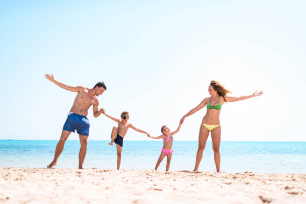 istock Young happy family holding hands on the beach. 1448733578