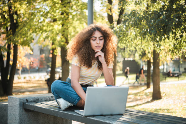 istock Beautiful girl working online from the park 1448734048