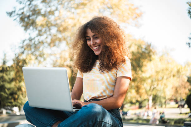 istock Girl sitting at the park and working online 1448734077